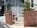大田区のカープ型レンガの門柱に白い門扉を取り付けたクローズ外構の施工例